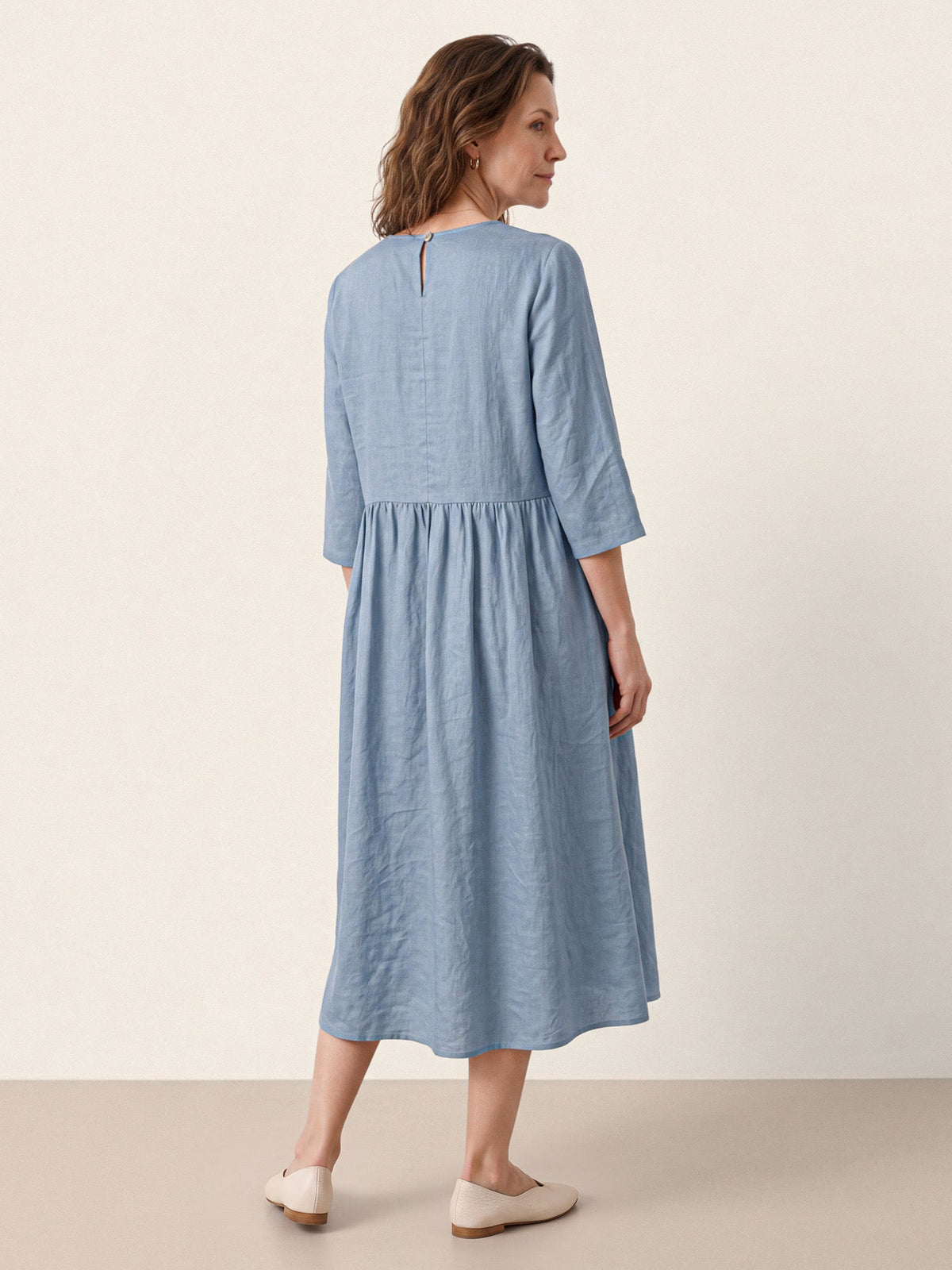 Rear view of a light blue midi dress with a gathered waist.