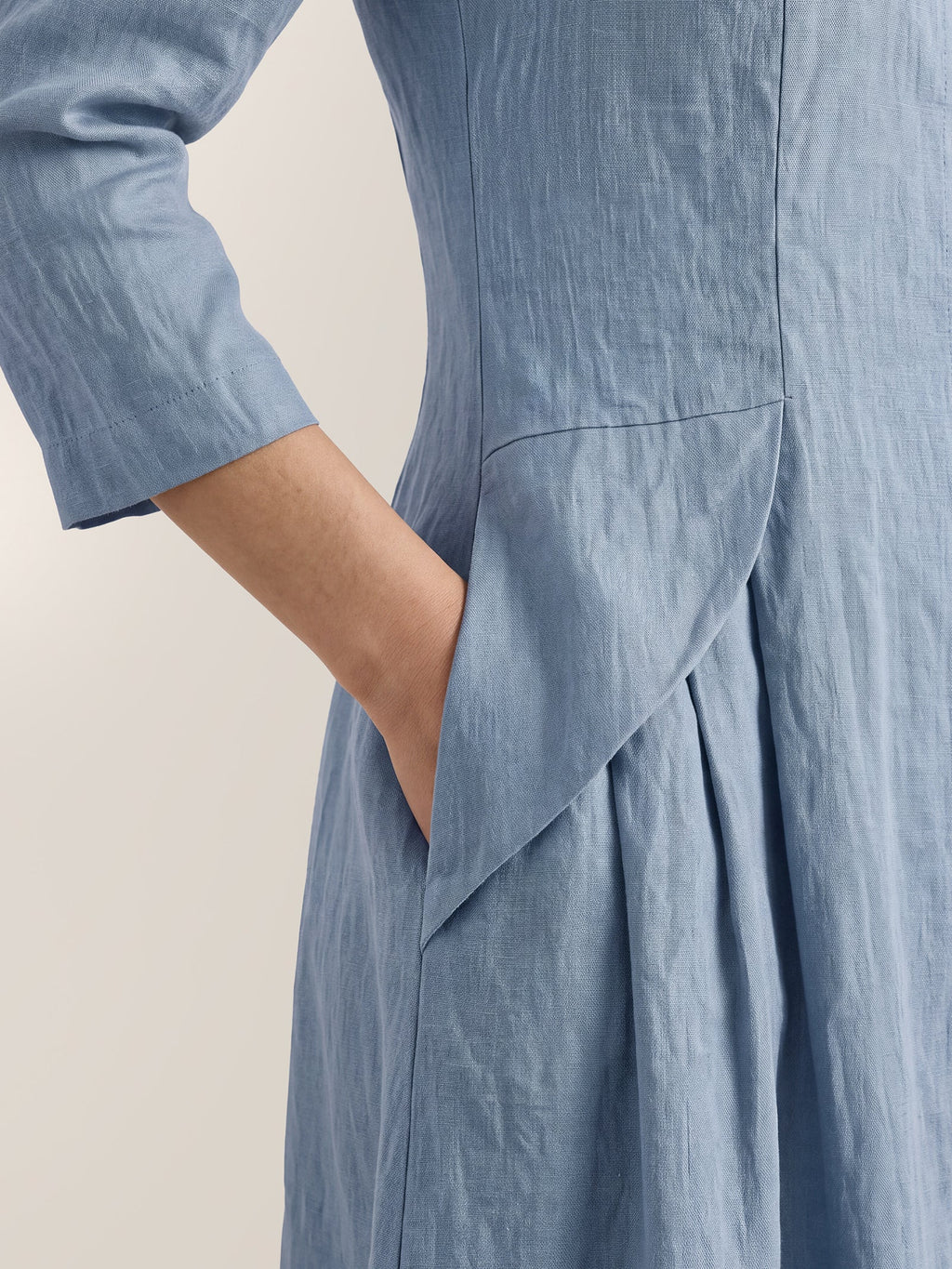 Close-up of a light blue dress showing a side pocket and angled waist seam.