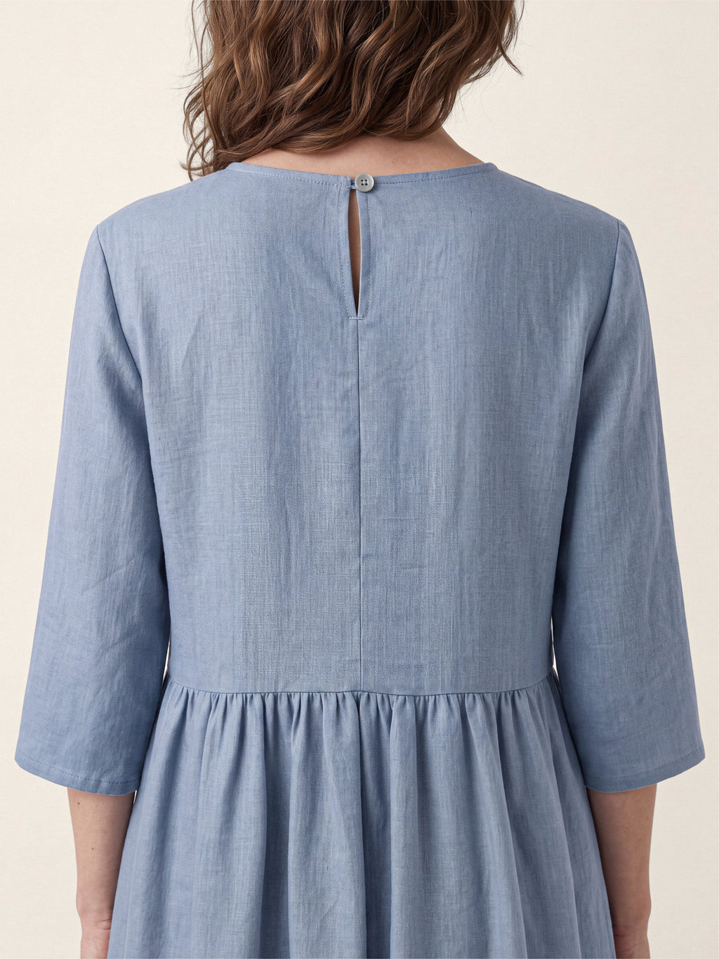 Rear close-up of a light blue dress showing a keyhole neckline and gathered waist.