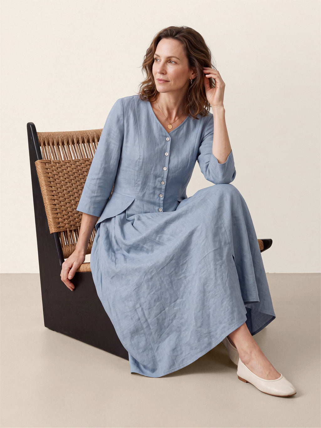 Woman seated in a chair wearing a light blue midi dress.