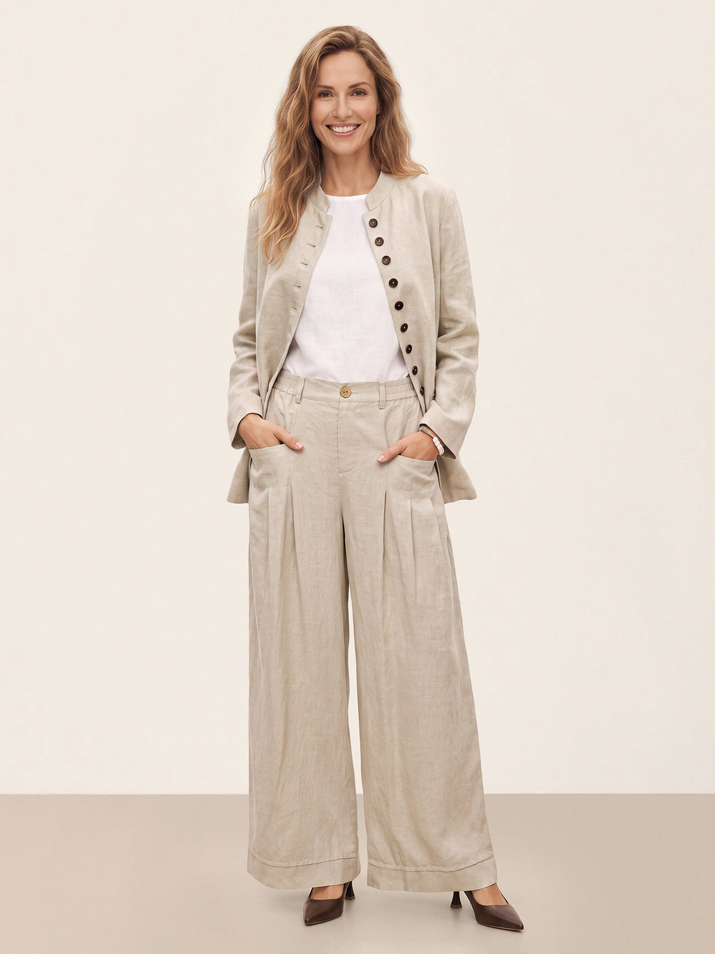 Woman wearing a beige jacket with matching wide-leg trousers.