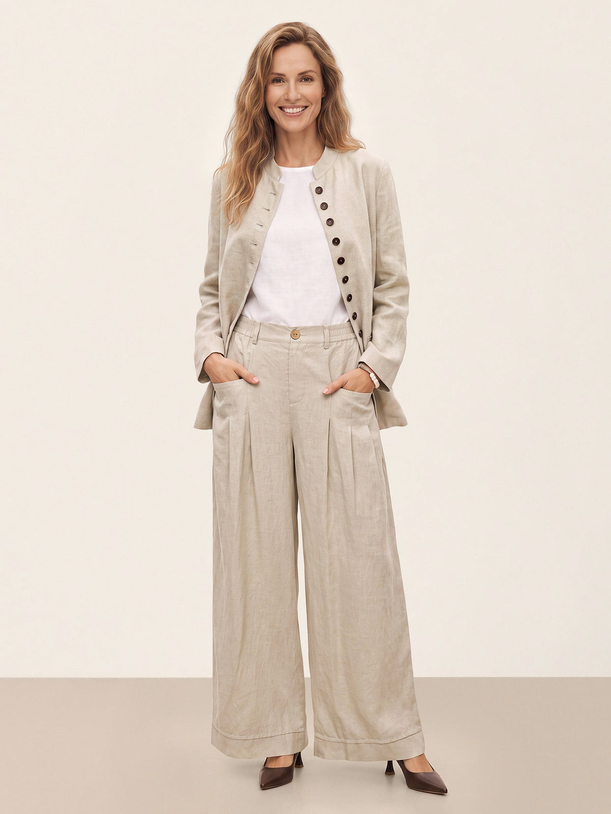 Woman wearing a beige jacket with matching wide-leg trousers.