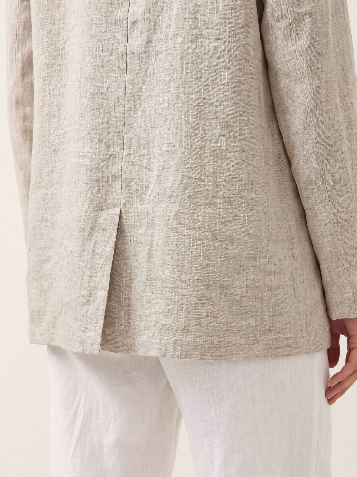 Close-up of the lower front and hem of a beige jacket.