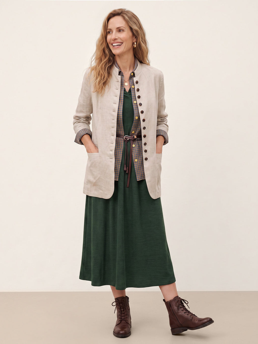 Woman wearing a beige jacket over a dark green dress.
