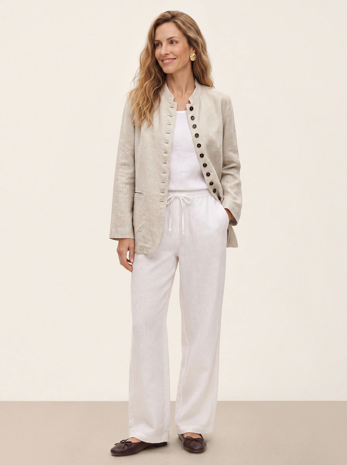 Woman wearing a beige jacket with white wide-leg trousers.