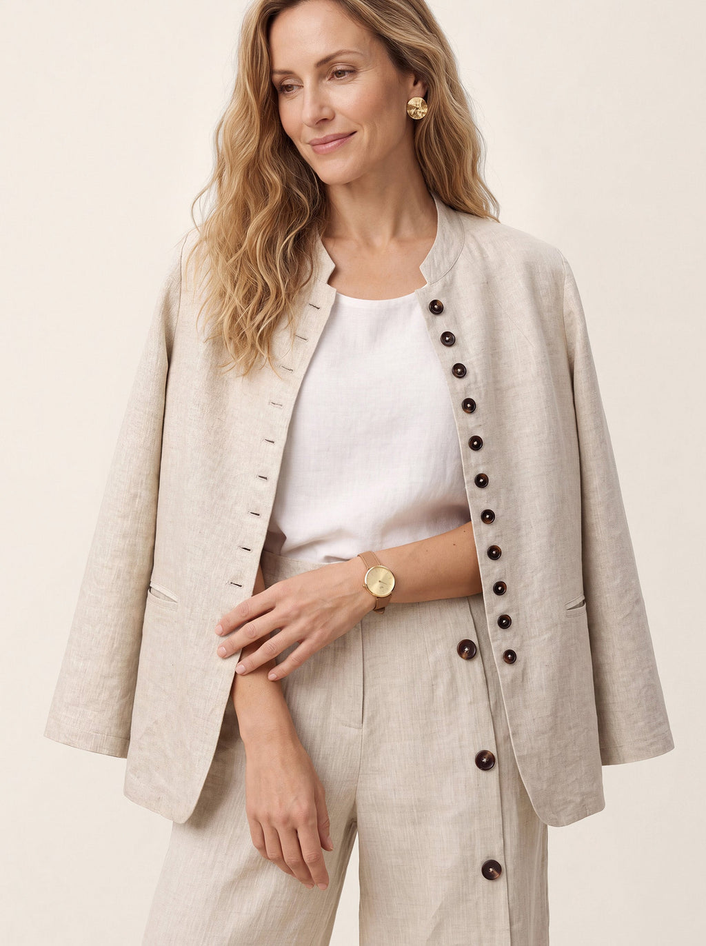 Beige collarless jacket worn open over a white top.
