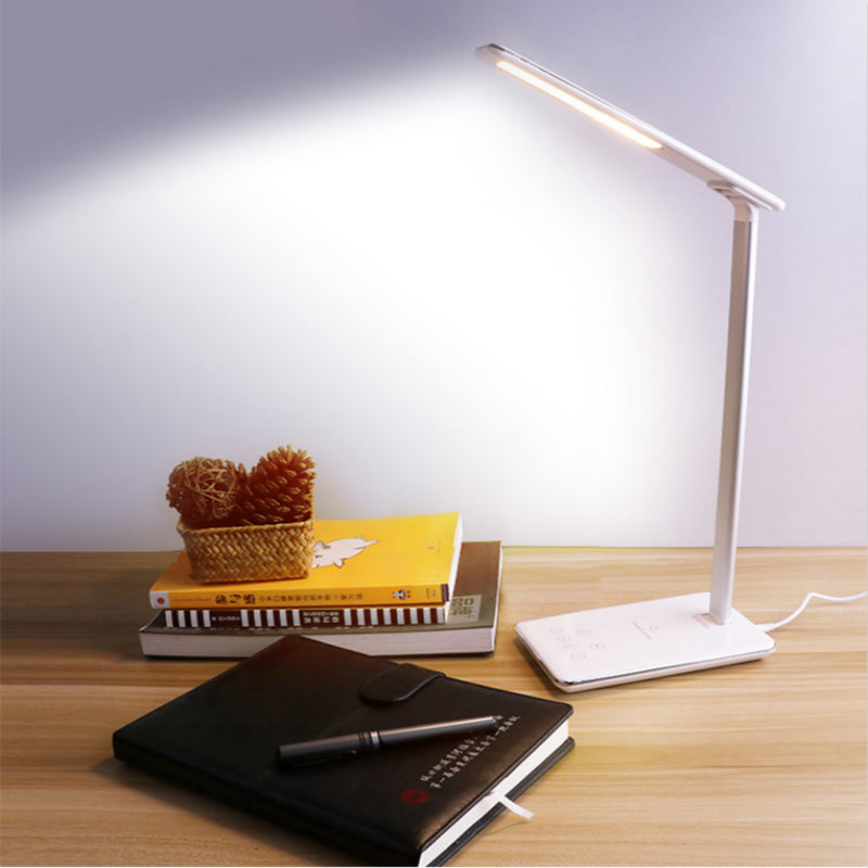 Illuminated white desk lamp on a wooden desk.