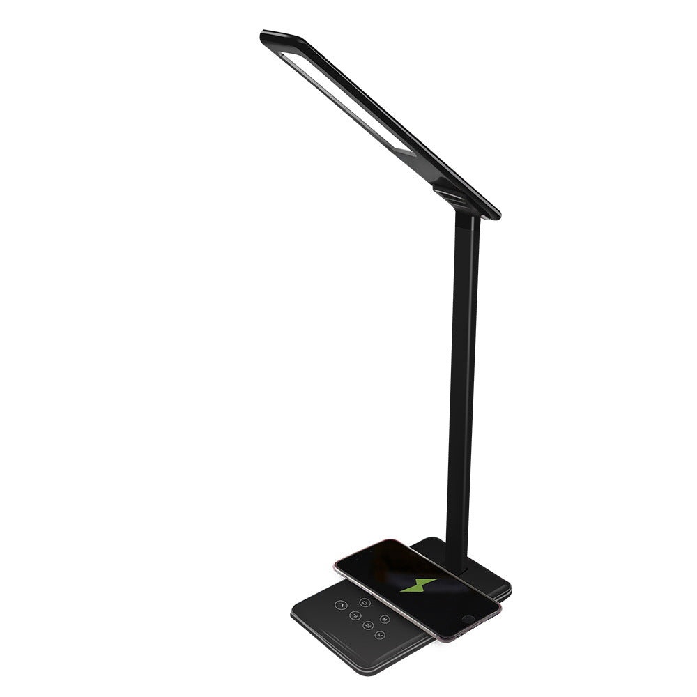 Black adjustable desk lamp with phone on charging base.