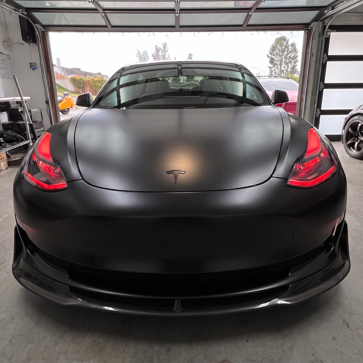 Black car with red headlight outlines in garage.