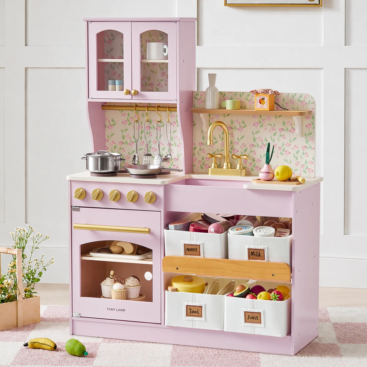 Pink toy kitchen with gold faucet and accessories.