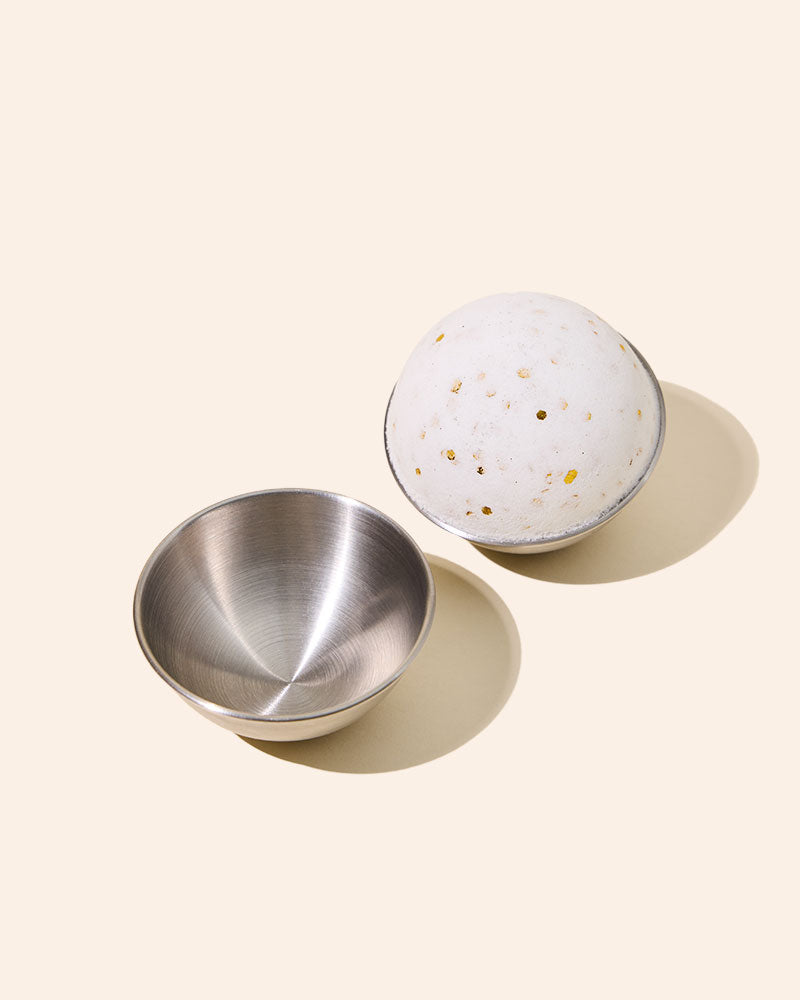 Open metal tin beside speckled round disc.