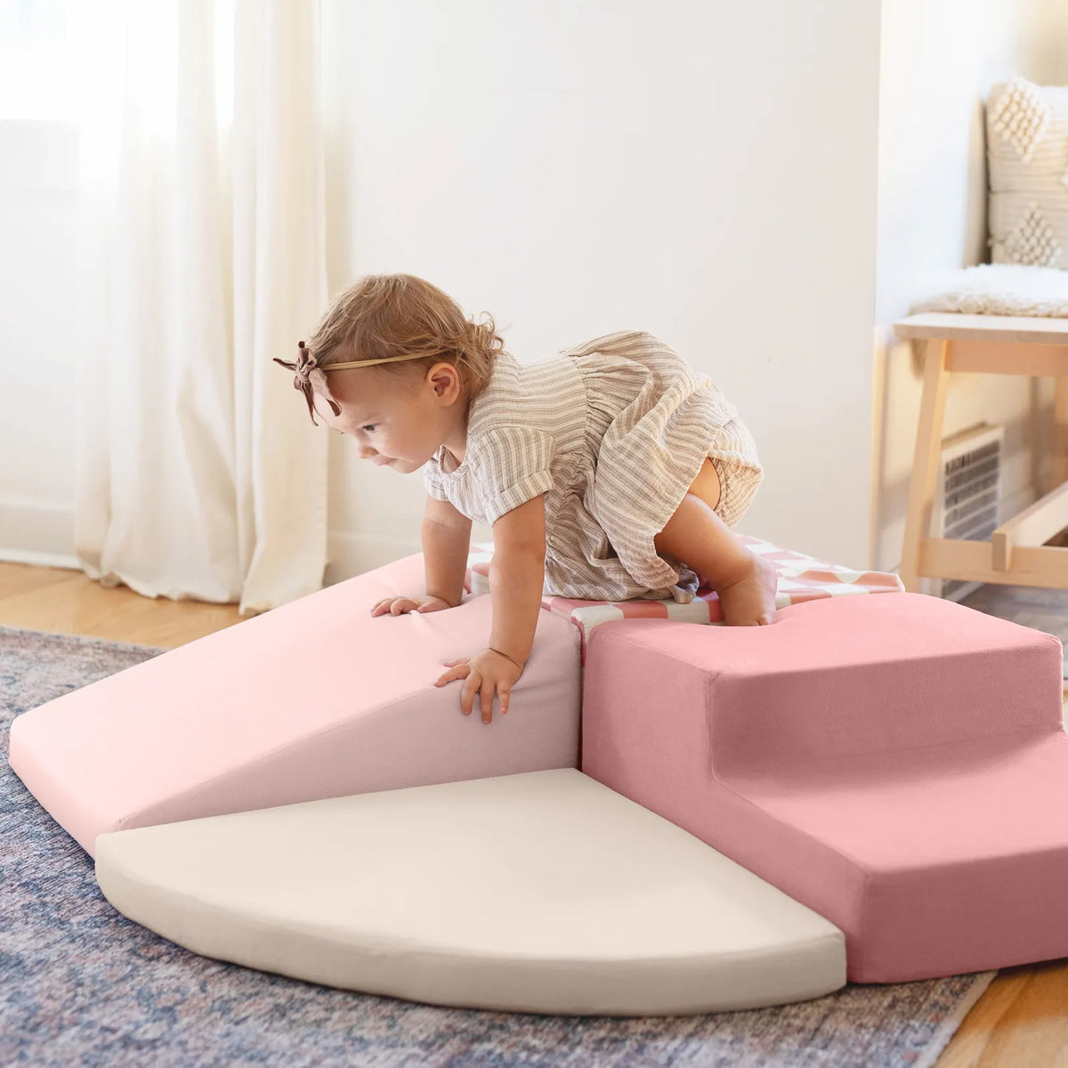 Toddler climbing pink foam blocks.