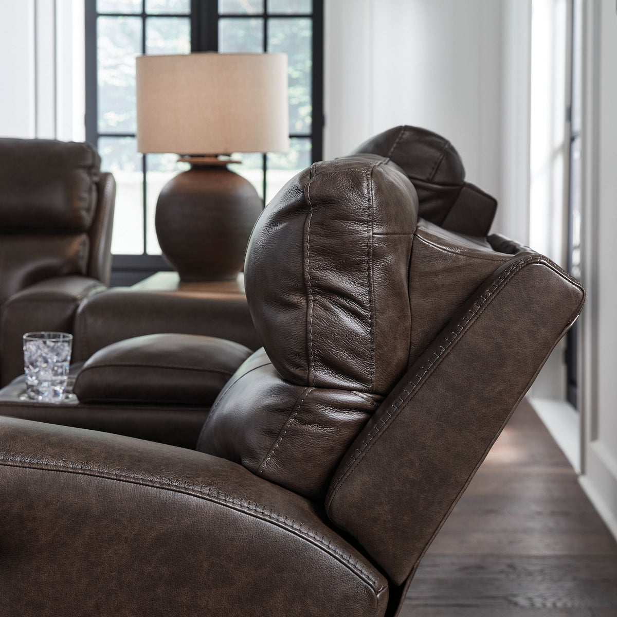 Side profile of brown reclining sofa beside a lamp.