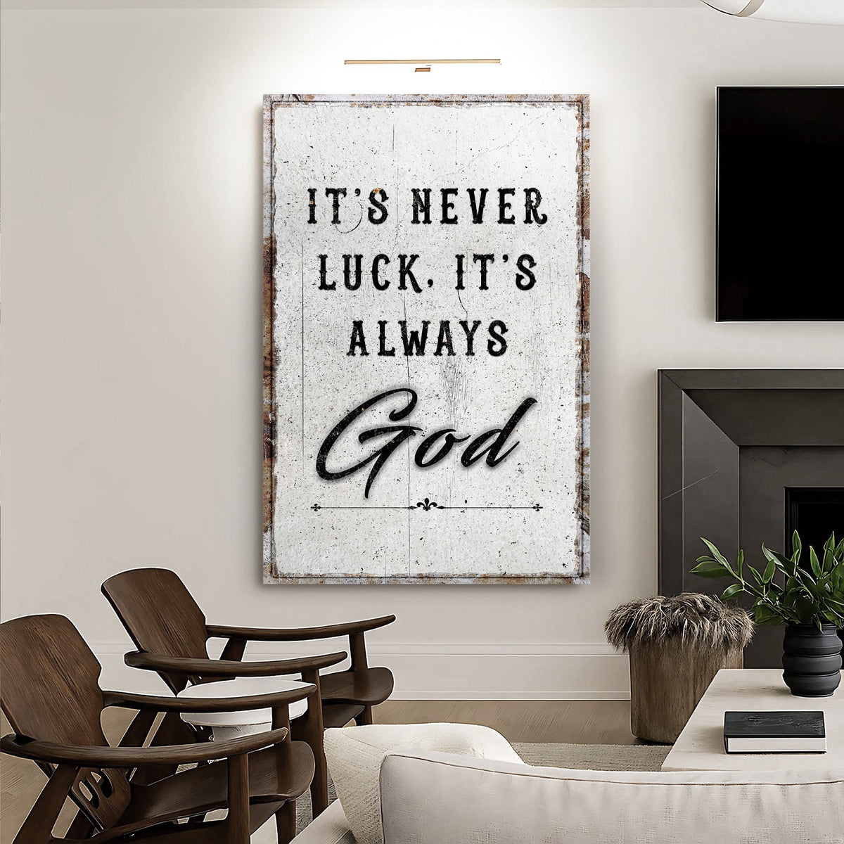 Distressed white It's never luck. It's always God canvas in a living room beside a fireplace.