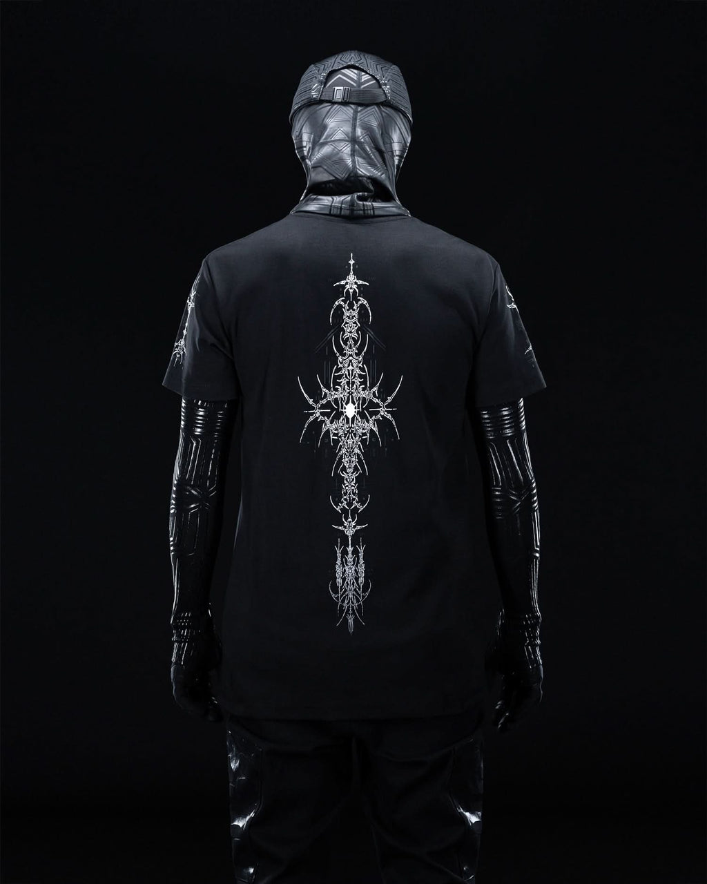 Rear view of masked model wearing black T-shirt with fine gray ornamental artwork.
