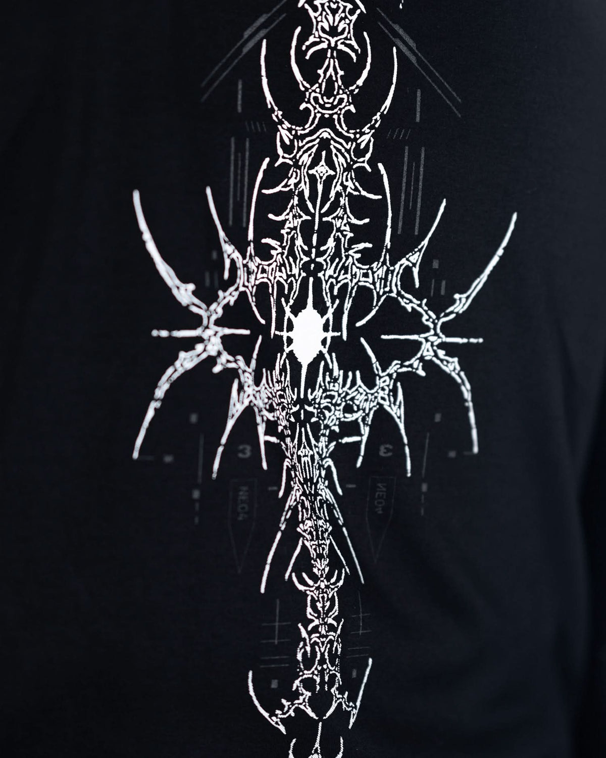 Close-up of upper rear emblem on black T-shirt with gray ornamental graphics.
