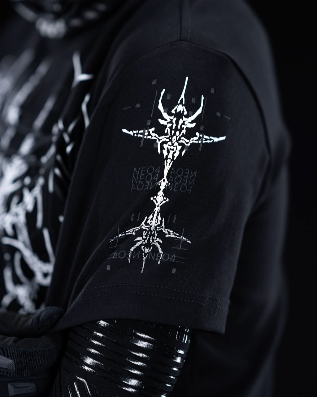 Close-up of sleeve emblem on black T-shirt with gray ornamental graphics.
