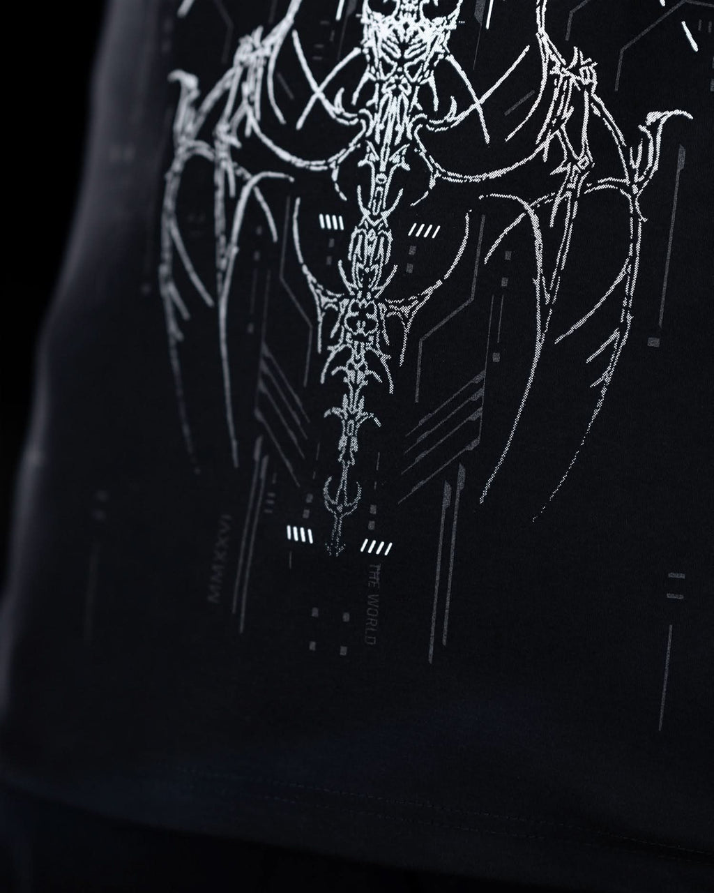 Close-up of lower front artwork on black T-shirt with gray ornamental graphics.