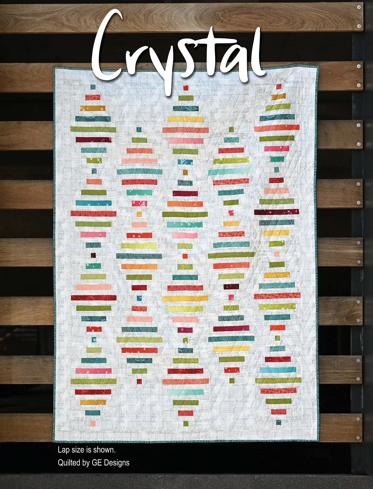 White quilt labeled Crystal with colorful geometric rows.