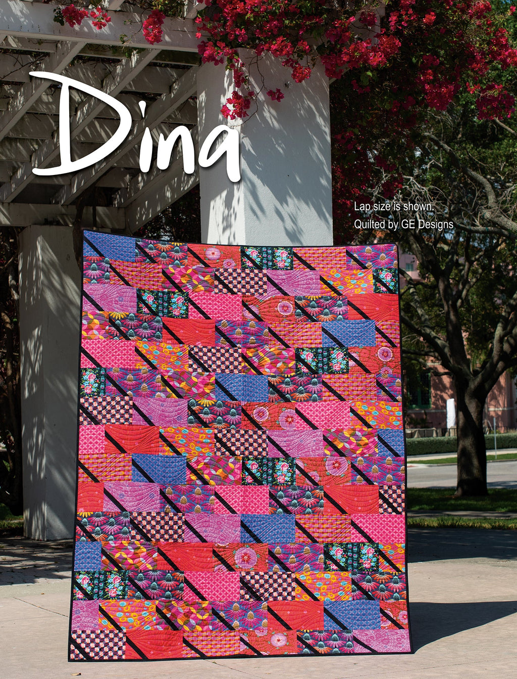 Pink geometric quilt labeled Dina displayed outdoors.