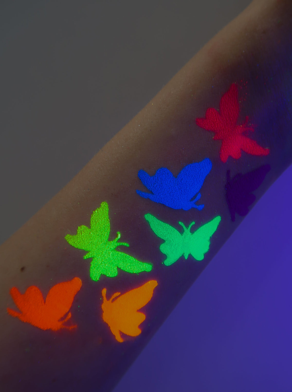 Colorful leaf-shaped swatches on forearm under dark lighting.