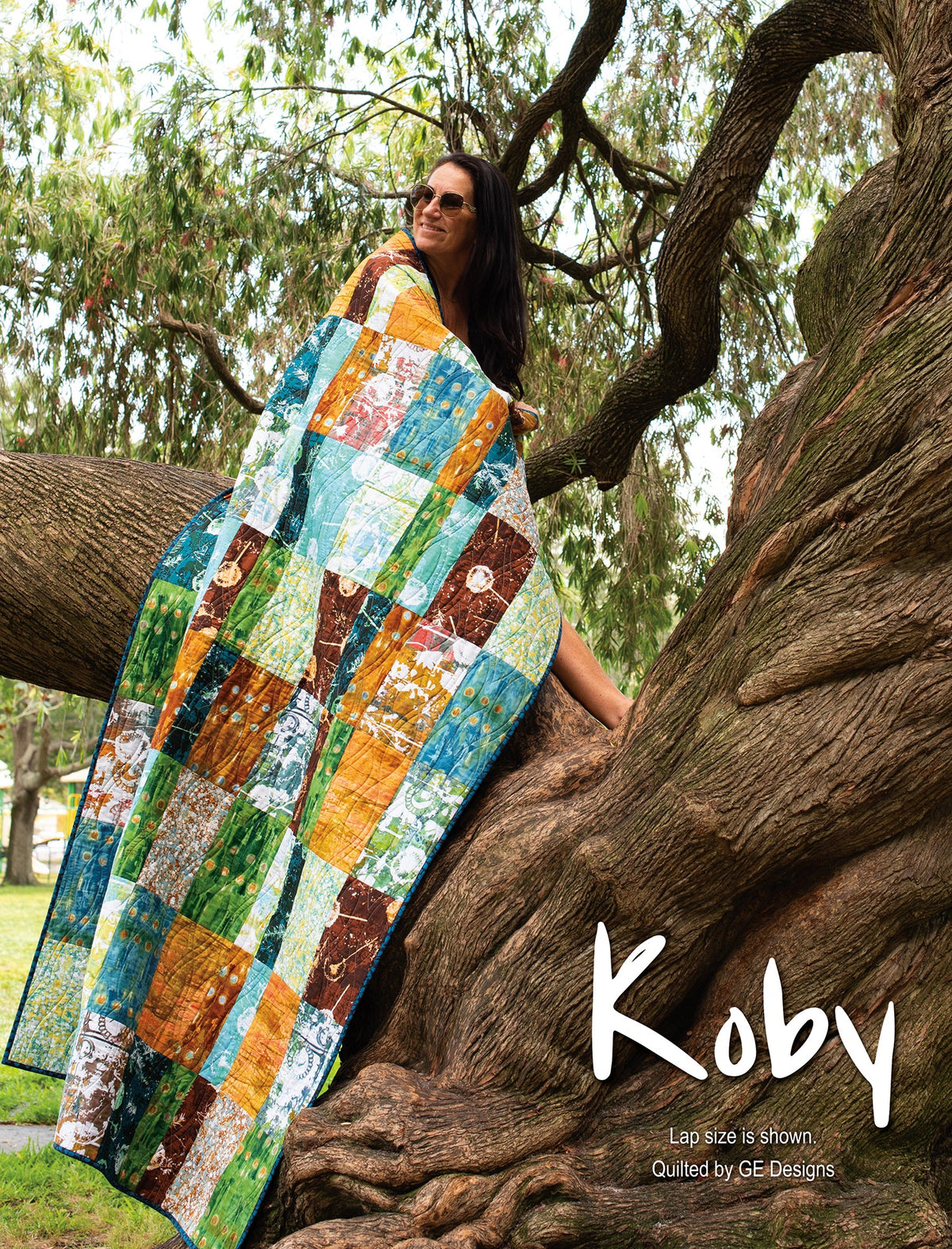 Person holding a colorful patchwork quilt labeled Koby.