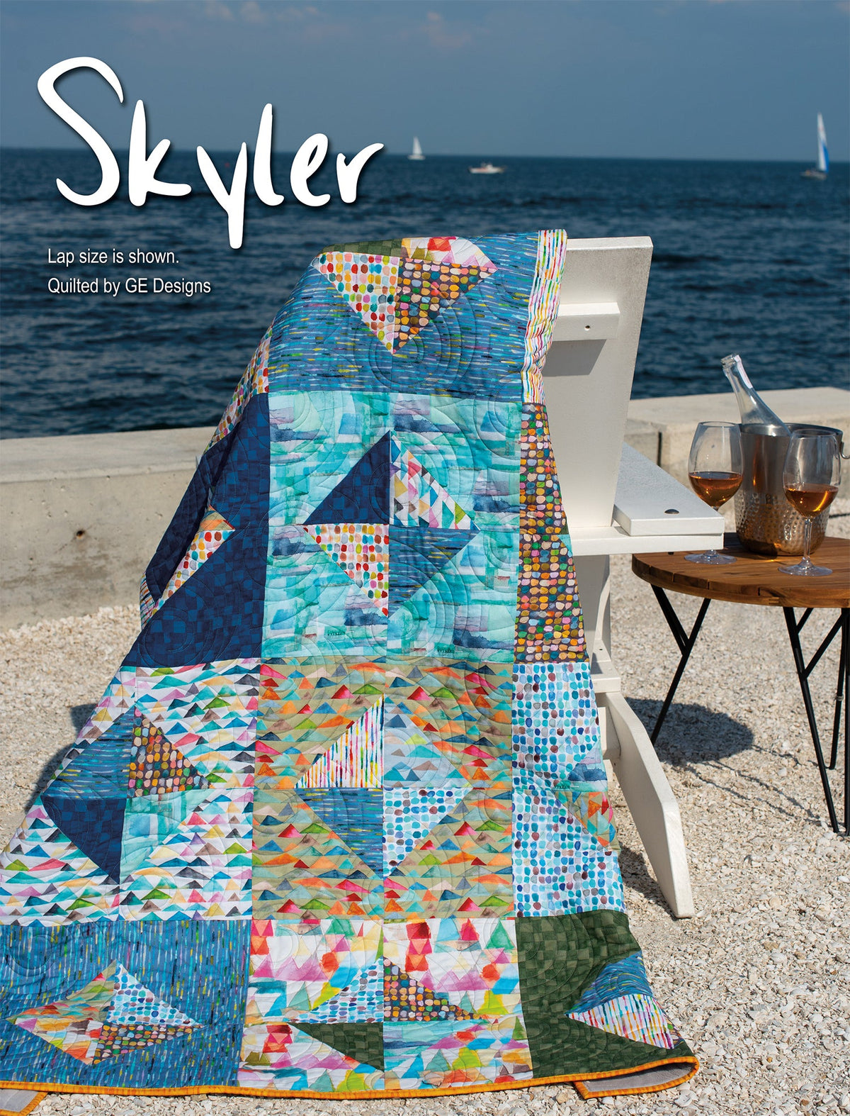 Turquoise patchwork quilt labeled Skyler beside a chair.