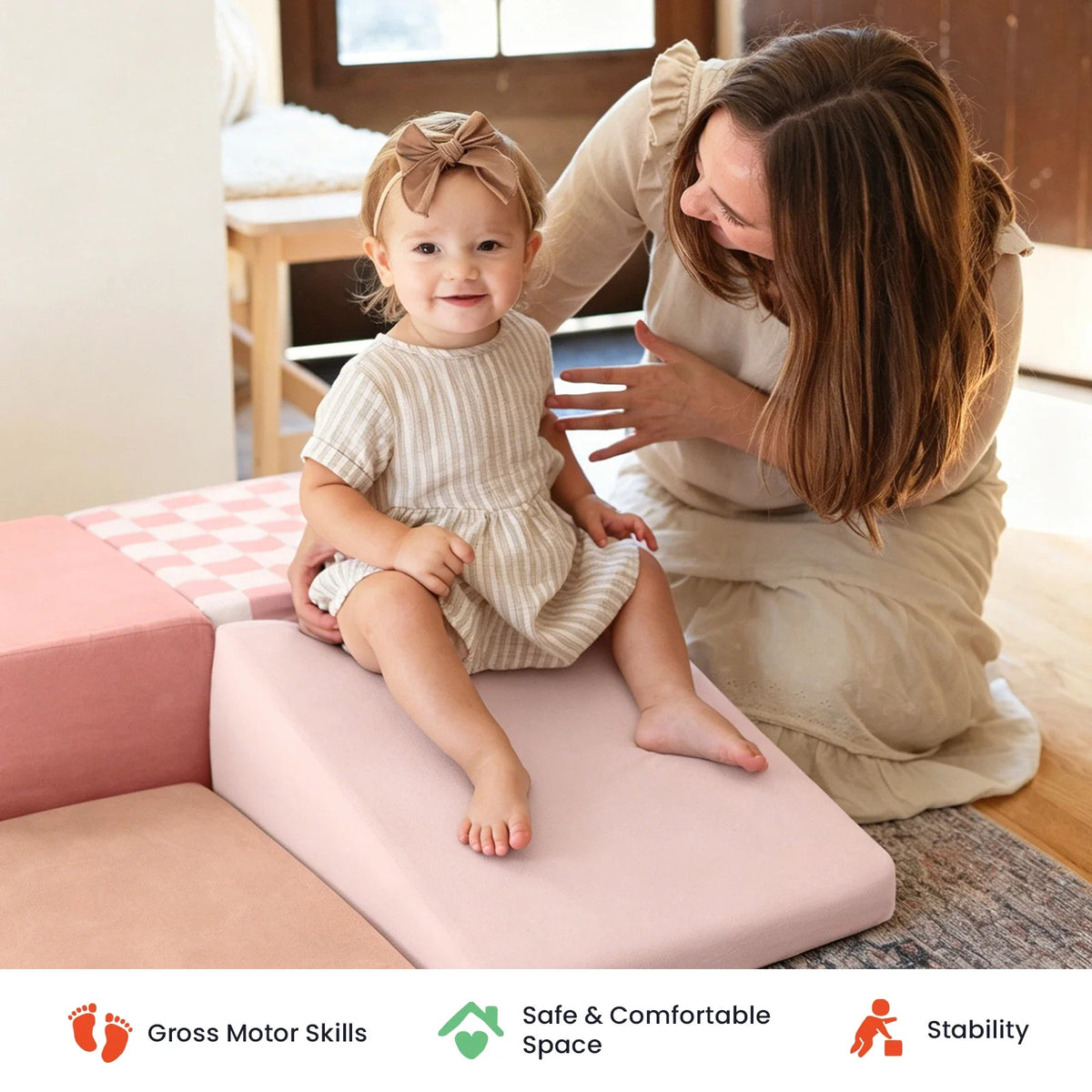 Woman helping a toddler sit on foam climbing blocks.