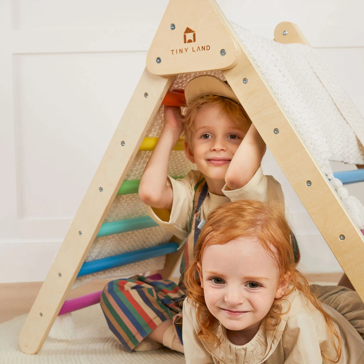 Children peeking through a colorful climbing triangle.