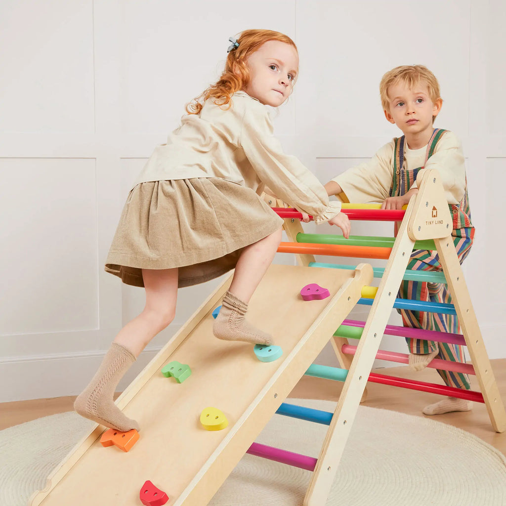 Two children playing on a colorful climbing ramp.