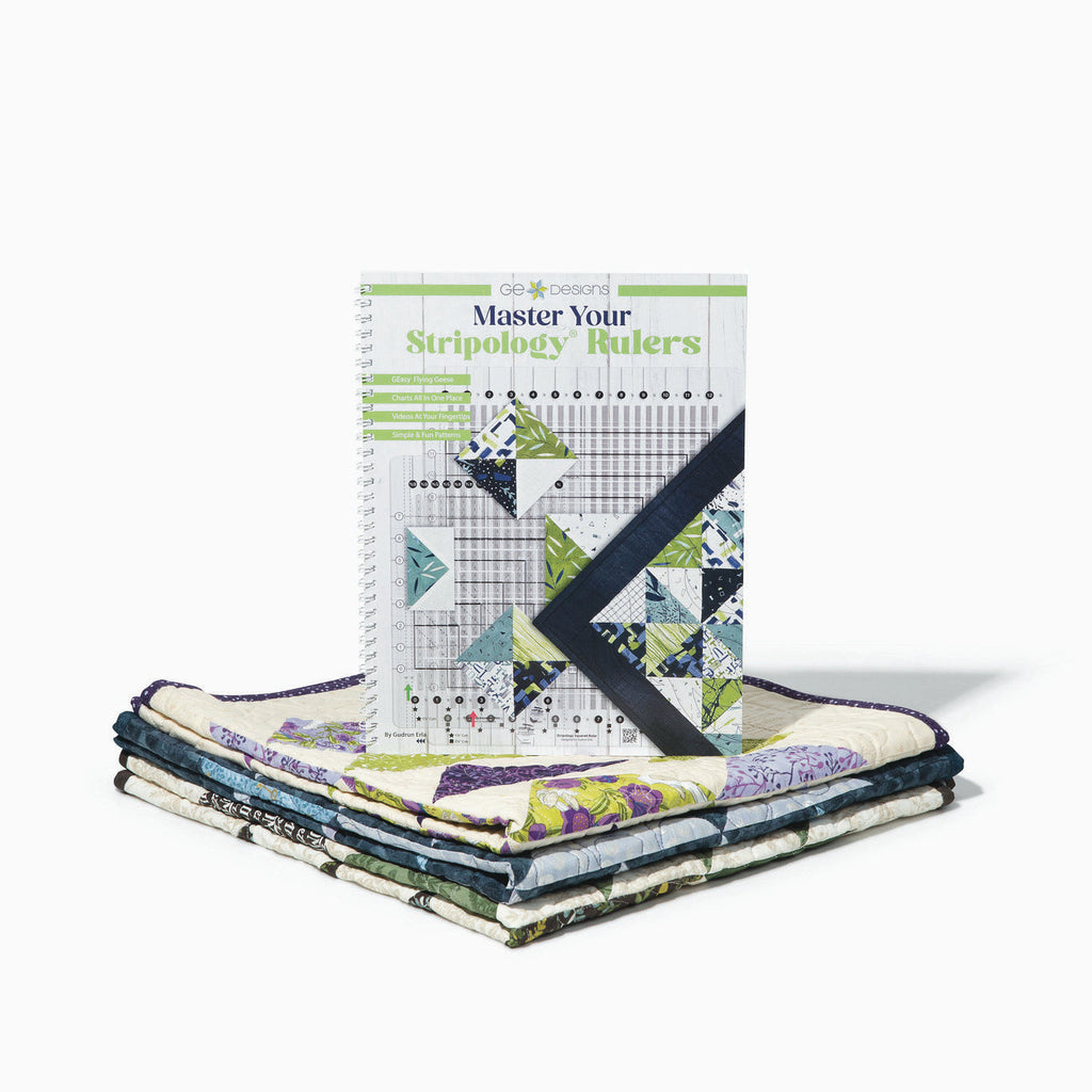 Master Your Stripology Rulers book beside folded quilts.